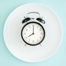 Photo of a clock on a plate with cutlery on either side.